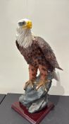 Hand-painted polyresin sculpture of a bald eagle perched on a rocky outcrop, raised on a stepped