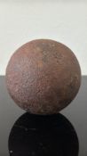 Cast iron solid roundshot cannonball, likely 18th-century ordnance, roughly spherical with