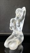 Frosted crystal figurine of a kneeling nude female with one arm raised, signed “Lalique ® France” to