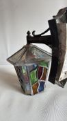 Wall-mounted leaded stained glass lantern with black metal bracket; hexagonal body glazed with