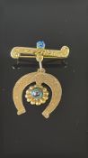 9ct Gold horse shoe pin brooch in scripted Na Zisi, pin holder not gold - Total Weight 1.7g