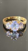 18-carat yellow-gold ring claw-set with an oval 8×6 mm tanzanite flanked by two 5×4 mm oval
