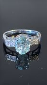 18k white gold ring centring an oval Paraiba tourmaline, approx 1.47 ct, flanked by four round