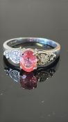 18k white gold ring centring an oval Ceylon padparadscha sapphire, approx 0.88 ct, flanked by two