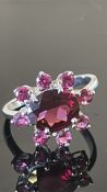 18ct white gold ring featuring an oval rhodolite garnet within a starburst surround of eight round