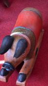 Hand-carved and polychrome hardwood rocking pig, the crouched figure with black ears and hooves, red