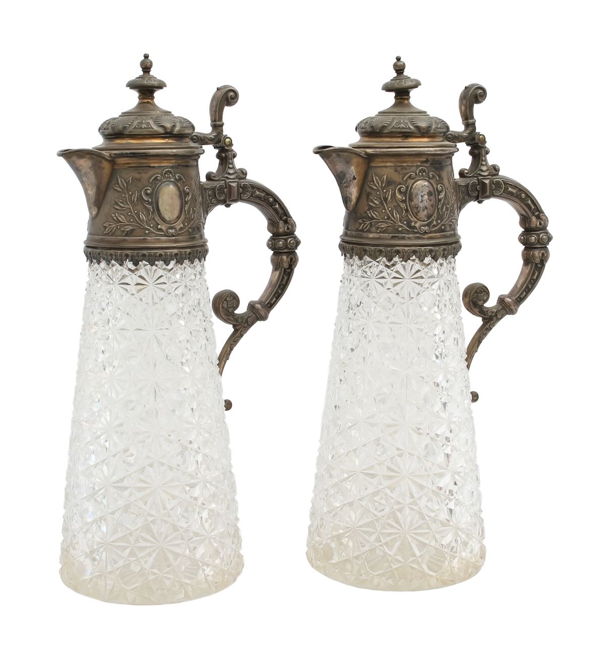 A pair of German silver mounted and cut glass claret jugs