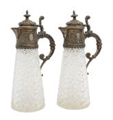 A pair of German silver mounted and cut glass claret jugs