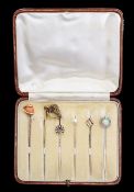 A group of six assorted stick pins, in a fitted case