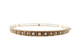 An Edwardian seed pearl hinged oval bangle