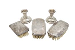 Three George V silver brushes, and a pair of silver dwarf candlesticks