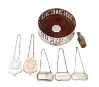 A group of five silver decanter labels, a Millennium coaster and a Peruvian silver mounted cork