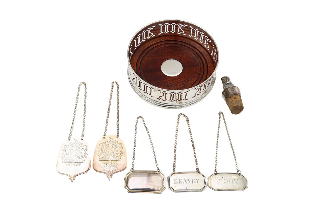 A group of five silver decanter labels, a Millennium coaster and a Peruvian silver mounted cork - Image 1 of 2