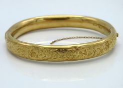 An 18ct gold bangle with chased decor, some bumps