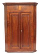 A Georgian mahogany wall mounted corner cabinet wi