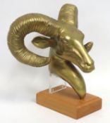 A mounted brass model of rams head set on oak plin