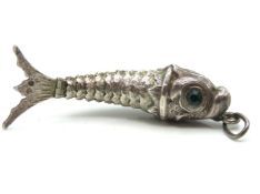 A silver articulated fish pendant with green glass