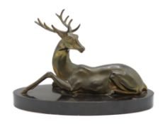 An art deco spelter sculpture of a recumbent stag on polished slate plinth, small chip to plinth, 31