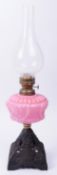 19TH CENTURY OIL LAMP WITH CAST IRON BASE AND PINK GLASS RESERVOIR
