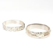 Two hallmarked silver engraved hinged bangles. The bangles to include a hallmarked silver hinged