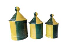 THREE LATE 20TH CENTURY CERAMIC GRADUATING LIDDED GREEN AND YELLOW POTS