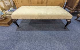 Long Low Bedroom Stool, upholstered in cream fabric, raised on four ebonised legs.