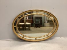 A George III style oval giltwood and composition marginal plate wall mirror, width 124cm, height