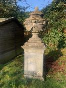 A large 18th century natural stone vase, carved with rosettes and drapery swags, raised on a