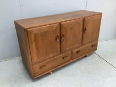 An Ercol Windsor elm dining suite comprising a sideboard, six ladderback dining chairs and extending