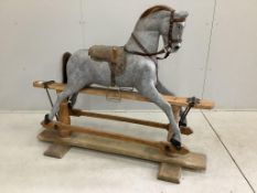 An early 20th century dapple grey rocking horse on pine safety frame, length 136cm, height 108cm.