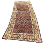 An antique Senneh red ground hall carpet, 325 x 128cm