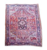 An antique Heriz brick red ground carpet with central
