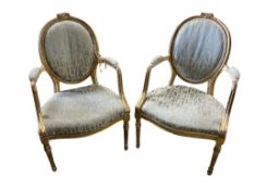 A pair of 18th century carved giltwood open elbow chairs
