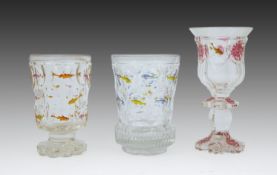 Two Bohemian transparent enamelled ‘fish’ beakers, and a similar faceted goblet, c.1840-60