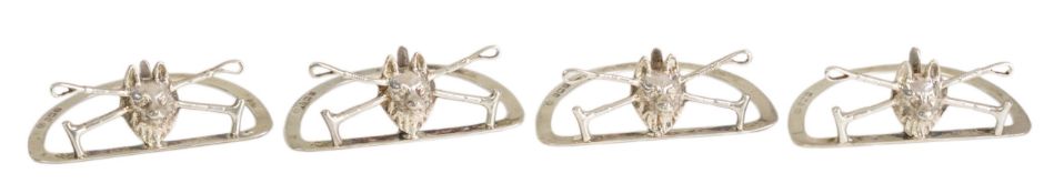 A cased set of four George V silver menu holders, modelled as a fox head with crossed riding crops,