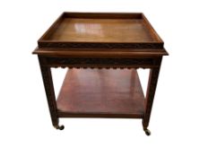 An early 20th century carved walnut square two tier occasional table, with brass caps and casters,