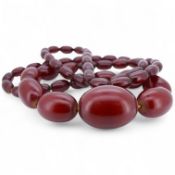 A cherry-coloured bakelite 'amber' necklace, composed of graduated oval beads measuring