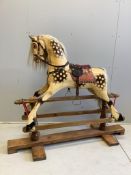 A carved wood dapple grey rocking horse on a pine safety frame, with glass eyes and leather tack,