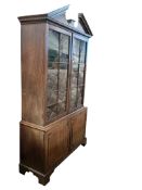 A George III mahogany library bookcase, the top surmounted with a broken architectural pediment,