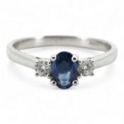 A sapphire and diamond three-stone ring, claw-set with an oval sapphire weighing approximately 0.