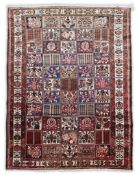 A Baktiari carpet woven with panels of flowers and geometric motifs within a triple floral border,