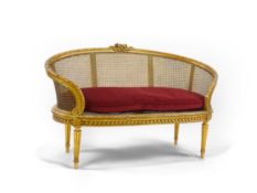A late 19th / early 20th century French caned giltwood and composition canapé with floral crest rail