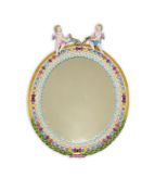 A Meissen figural oval mirror, late 19th century, with jewelled, flowerhead and stiff leaf border,