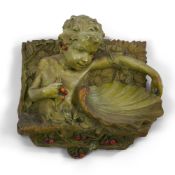 A large Austrian cold painted terracotta wall plaque, by J. Pilar, c.1900, modelled with a cherub