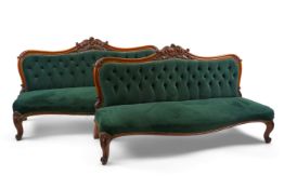 A pair of Victorian carved oak settees, recently reupholstered in deep buttoned green velvet, the