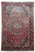 A Heriz brick red ground carpet woven with a lobed central medallion within a floral field and