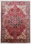 A Heriz red ground carpet woven with a central lobed medallion within a floral and geometric field