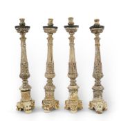 A set of four 18th century Italian silvered wood tall altar candlesticks with circular metal drip