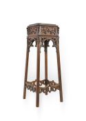 A late Victorian Gothic Revival carved oak pedestal with open scroll frieze on square splay legs and