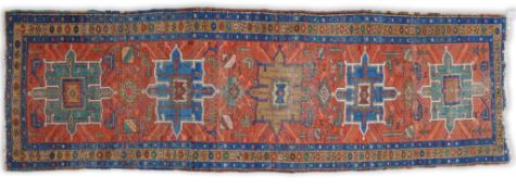 An early 20th century Caucasian brick red ground runner woven five hooked rectangular medallions